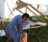 Eva, working on a scroll in camp at Pennsic, 2009. (Photo by Colin.)